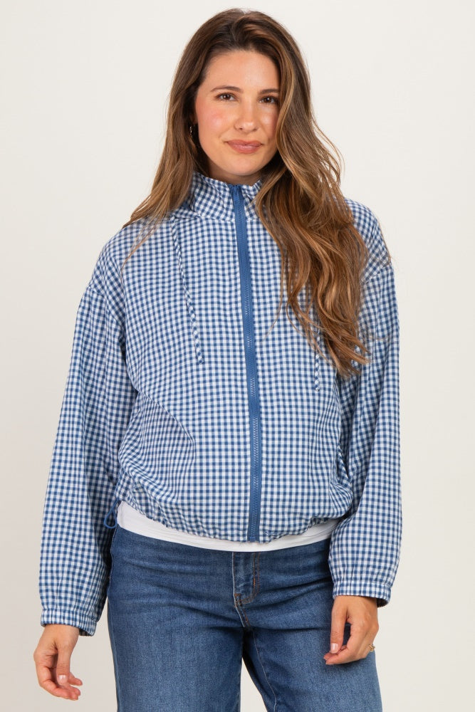 woman wearing a blue checkered maternity jacket with a zipper and front pockets, styled with blue jeans
