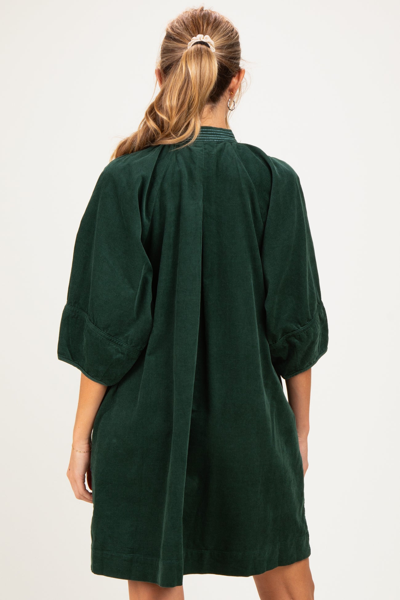 woman wearing a green corduroy maternity dress with a loose fit and puff sleeves, shown from the back