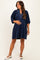 woman wearing a navy blue maternity dress with a v-neck and pleated detail, holding her baby bump