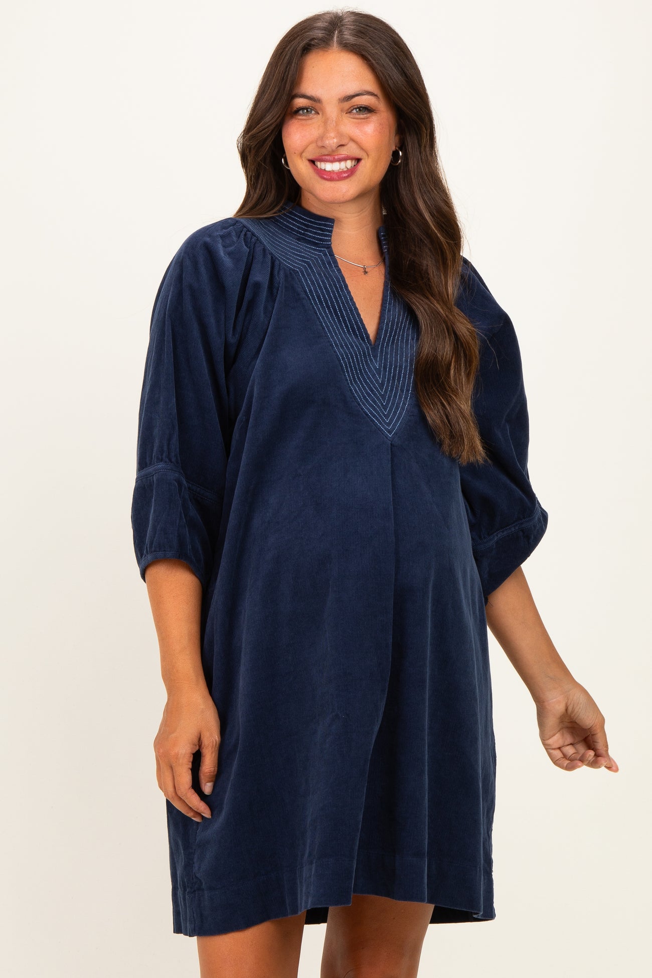woman wearing a navy blue corduroy maternity dress with a v-neck and puff sleeves