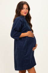 woman wearing a navy blue maternity dress with three-quarter sleeves and a gathered neckline, showing her baby bump