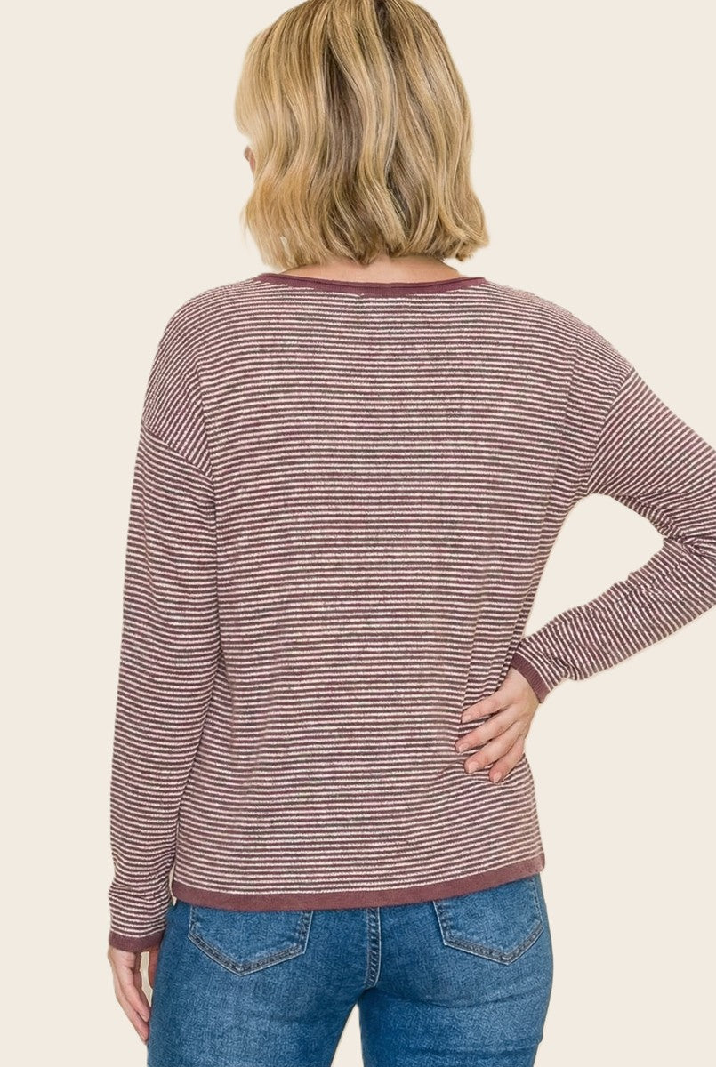 woman wearing a maroon and white striped long sleeve top, viewed from the back, paired with blue jeans