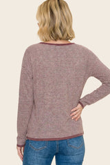 woman wearing a maroon and white striped long sleeve top, viewed from the back, paired with blue jeans