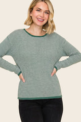 woman wearing a green and white striped long sleeve top with a relaxed fit and ribbed cuffs