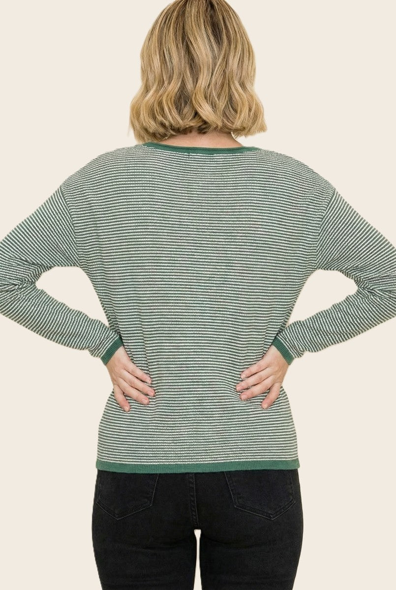 woman wearing a green and white striped long sleeve top, viewed from the back with hands on hips