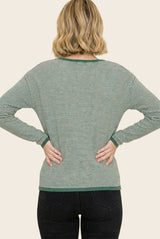 woman wearing a green and white striped long sleeve top, viewed from the back with hands on hips