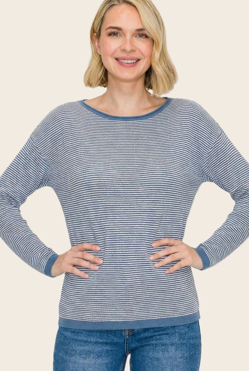 woman wearing a navy and white striped long sleeve top with a relaxed fit and blue trim, smiling at the camera