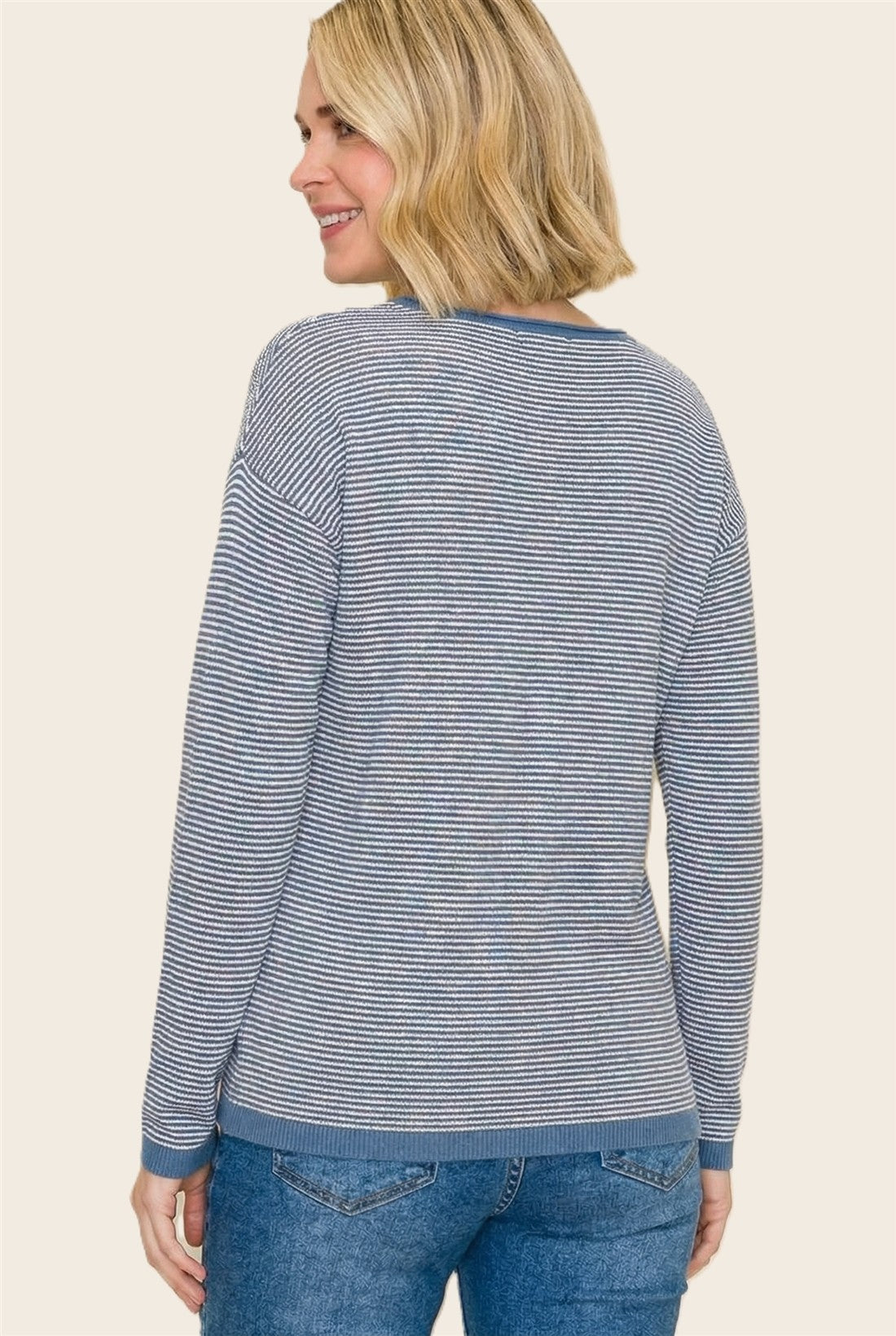 woman wearing a navy and white striped sweater with long sleeves and a rounded neckline, facing away from the camera