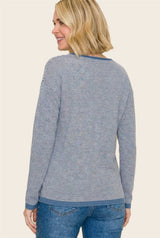 woman wearing a navy and white striped sweater with long sleeves and a rounded neckline, facing away from the camera