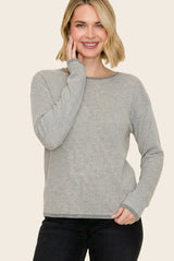 woman wearing a gray and white striped long sleeve sweater with a relaxed fit and round neckline