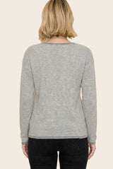 woman wearing a gray and white striped long sleeve sweater with a relaxed fit, viewed from the back