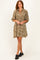 woman wearing a tan paisley print short-sleeve dress with a collared neckline and a loose fit
