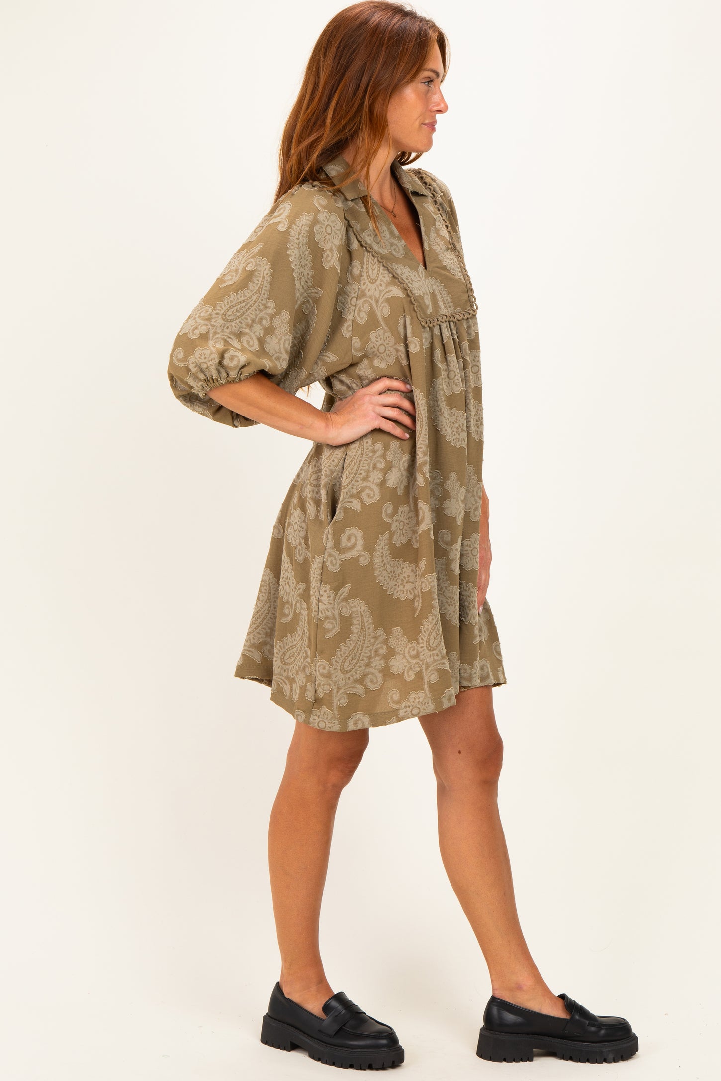 woman wearing a brown patterned short dress with a collared neckline and loose sleeves, styled with black platform shoes
