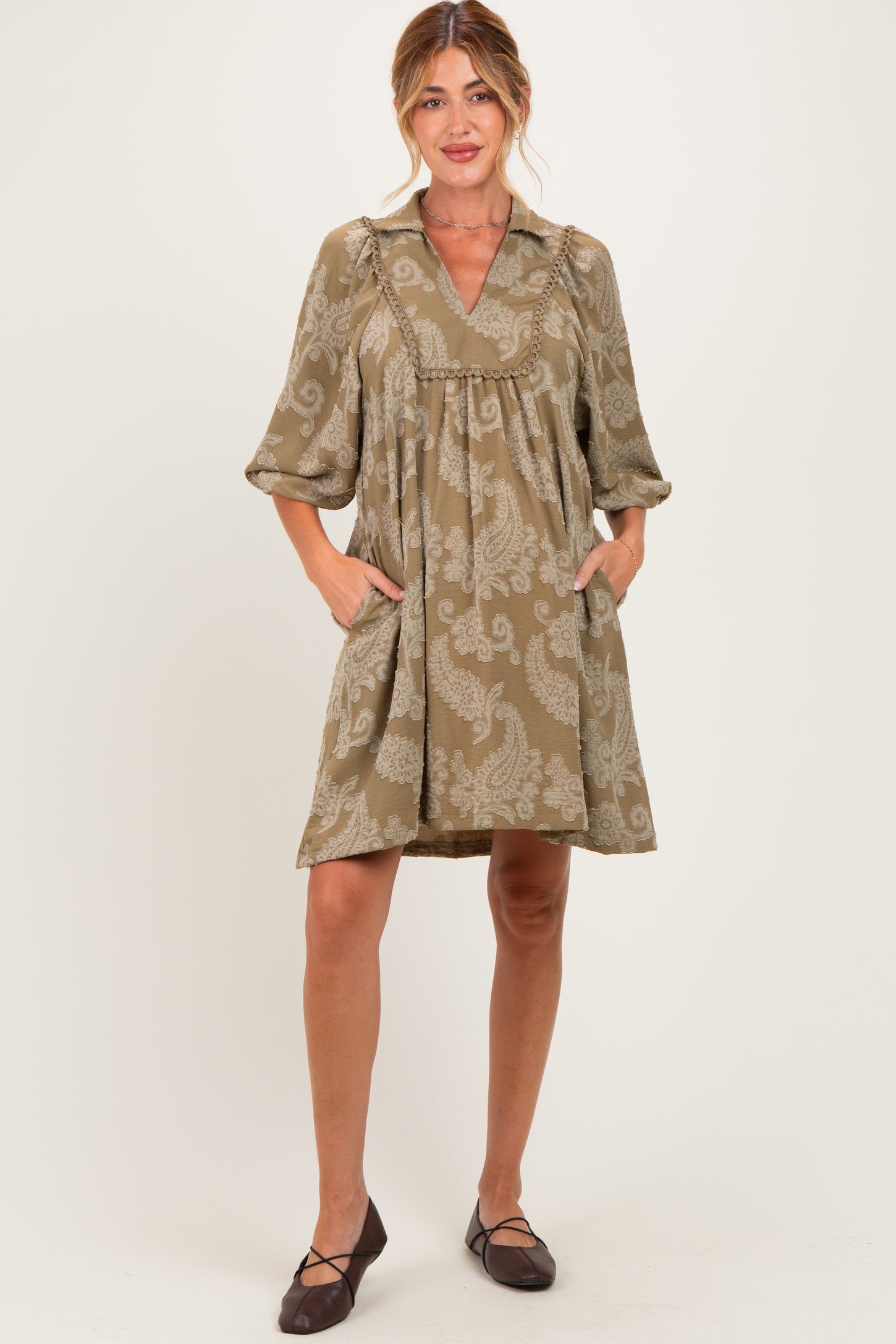 woman wearing a brown paisley maternity dress with a collar, short sleeves, and pockets