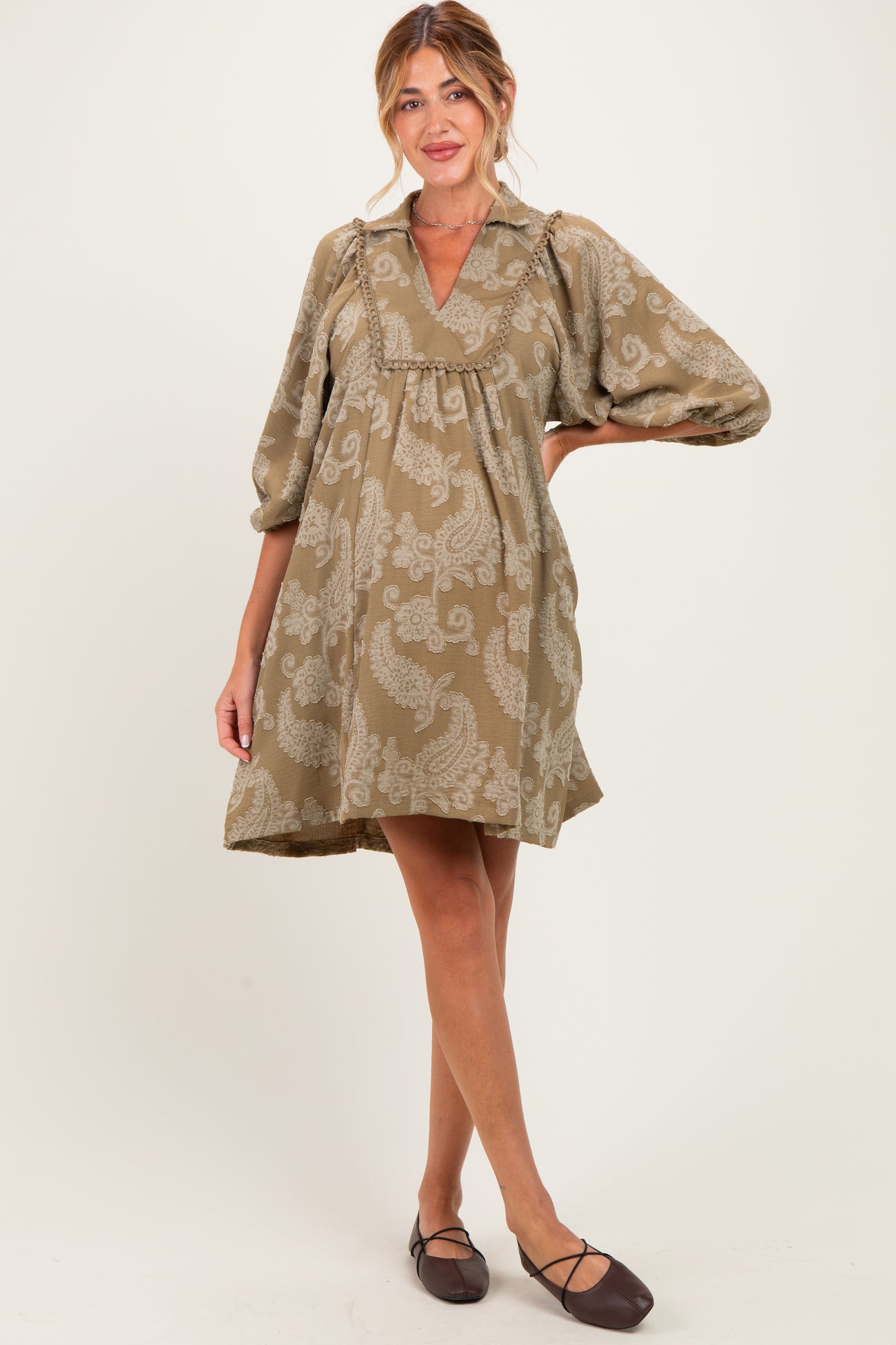 woman wearing a taupe paisley print maternity dress with a v-neck and balloon sleeves, showing her baby bump