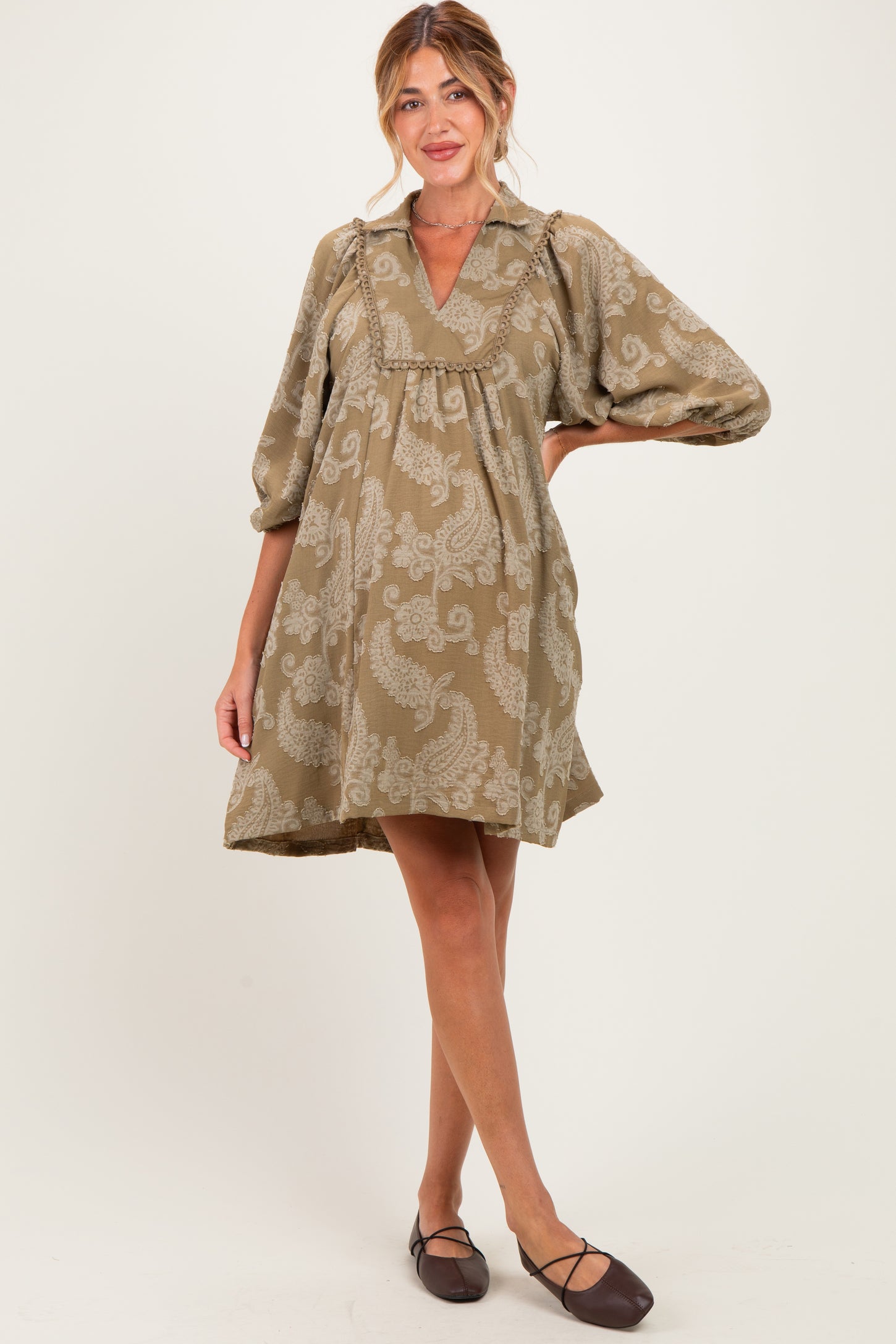 woman wearing a taupe paisley print maternity dress with a v-neck and balloon sleeves, showing her baby bump