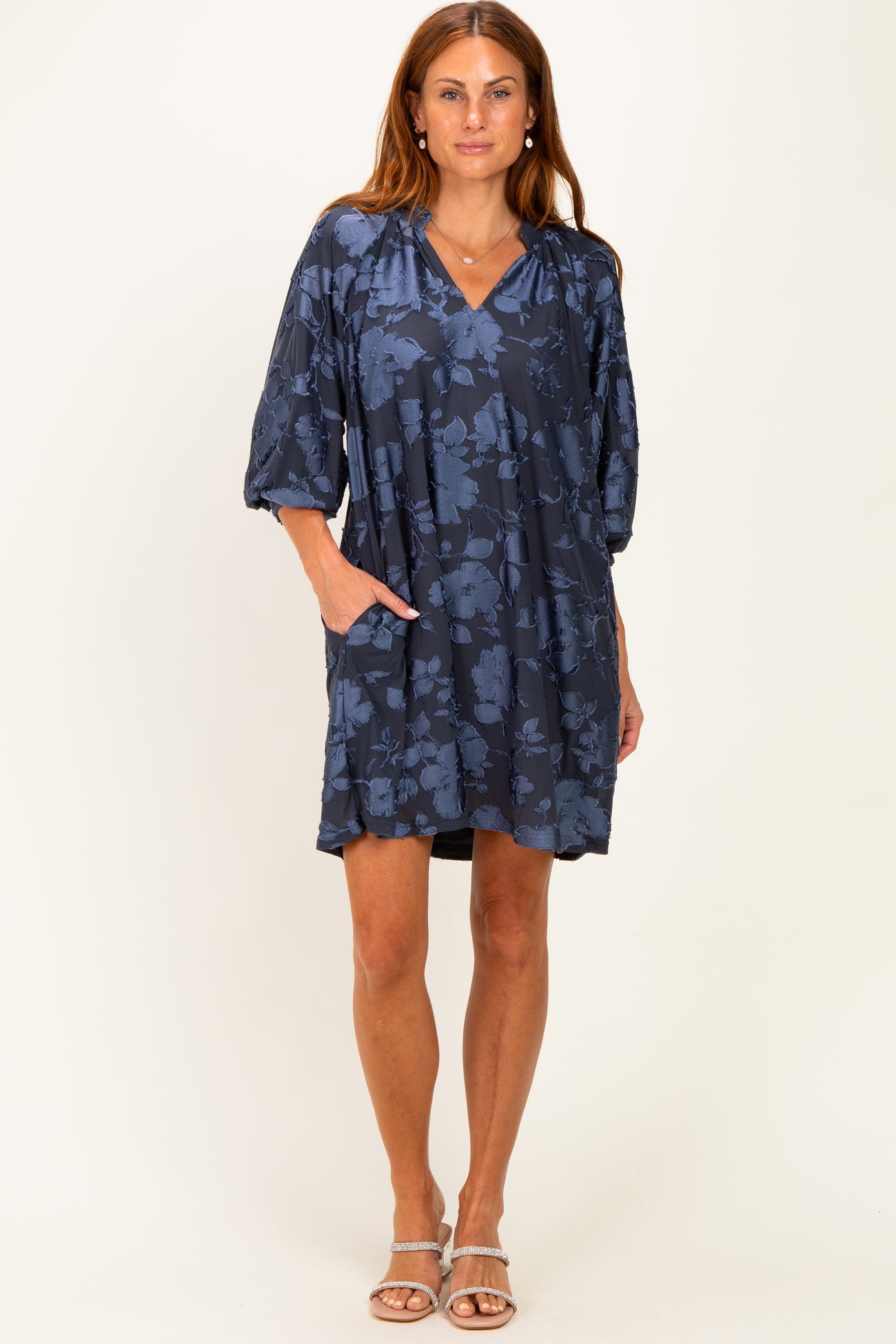 woman wearing a navy blue floral print dress with balloon sleeves and pockets
