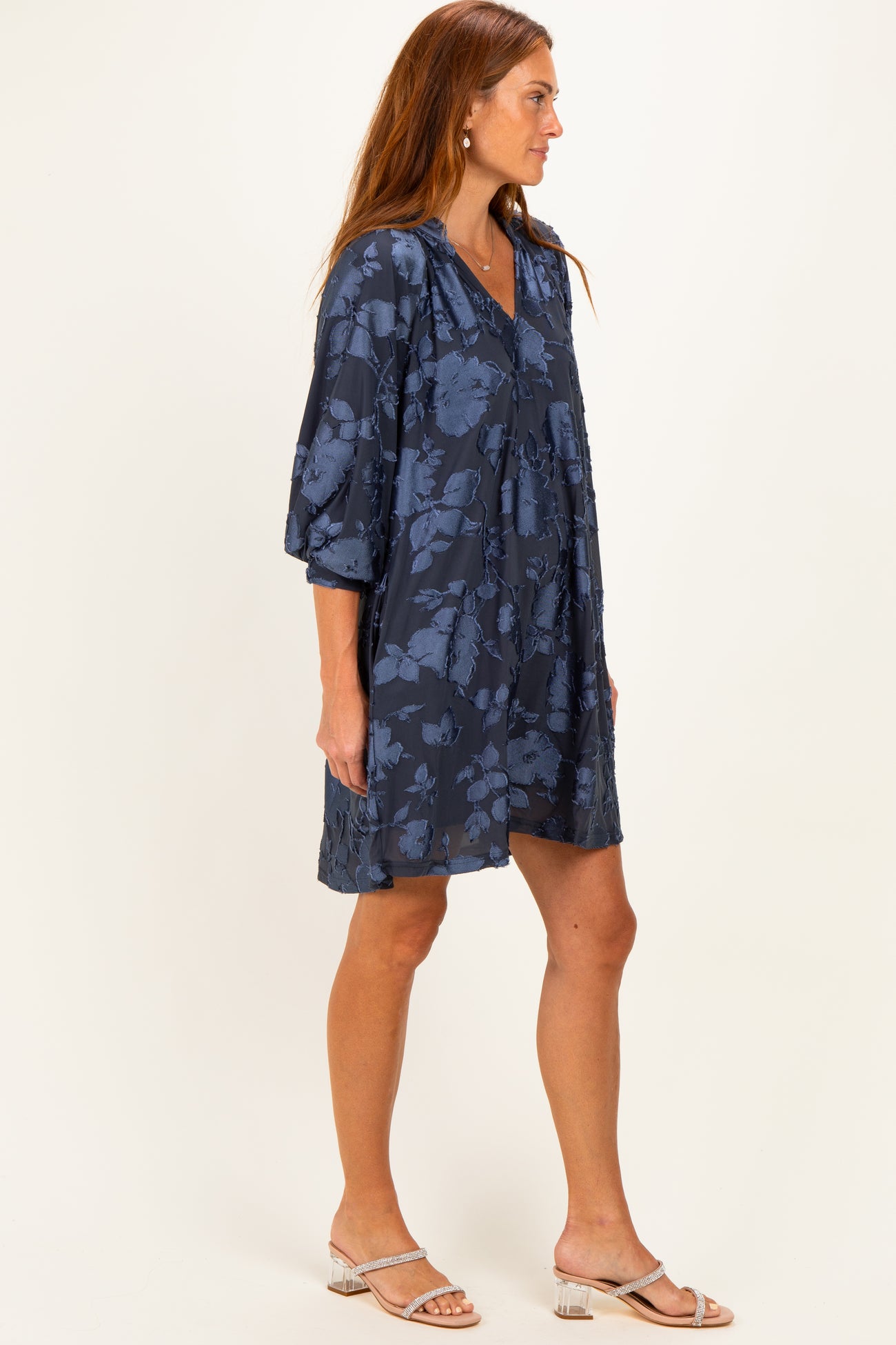 woman wearing a navy blue floral print dress with three-quarter sleeves and a V-neckline