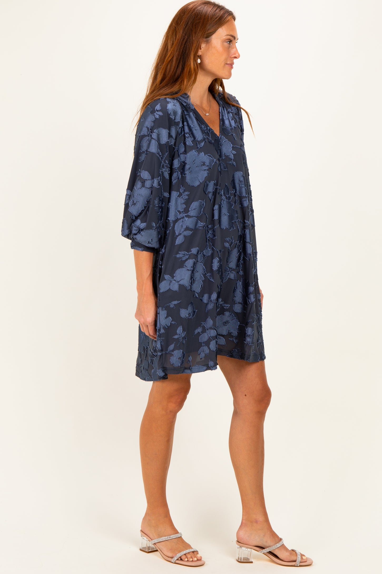 woman wearing a navy blue floral print dress with three-quarter sleeves and a V-neckline