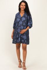 woman wearing a navy blue floral maternity dress with three-quarter sleeves and a visible baby bump