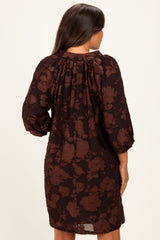 woman wearing a dark brown floral patterned maternity dress with puff sleeves, showing the back view