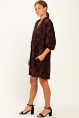 woman wearing a burgundy floral patterned short dress with puff sleeves and side pockets