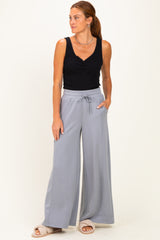 woman wearing a black tank top and light gray wide-leg pants with a drawstring waist and pockets