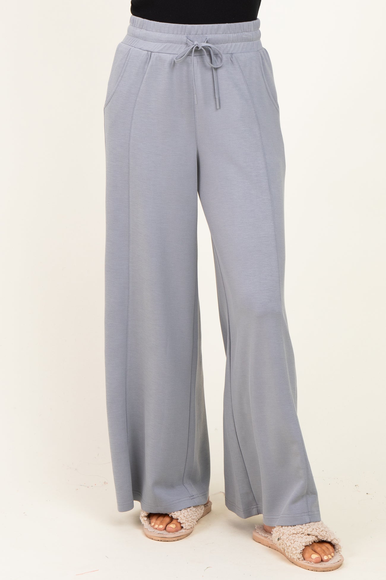 woman wearing light grey wide-leg lounge pants with drawstring waist and side pockets