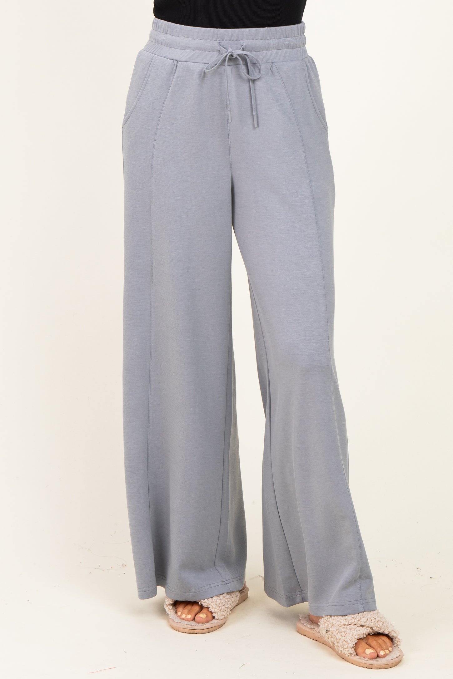 woman wearing light grey wide-leg lounge pants with drawstring waist and side pockets