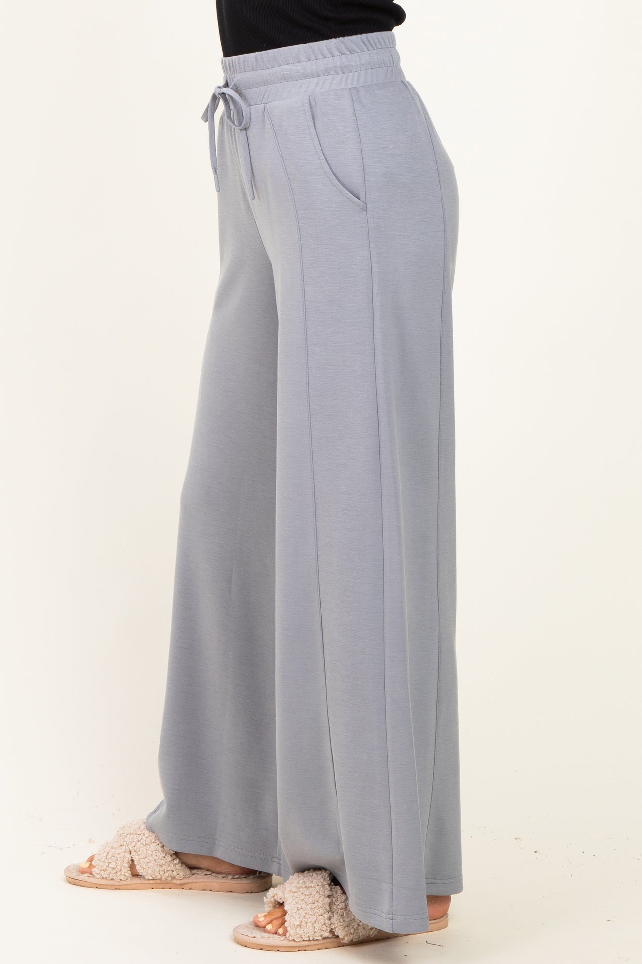 woman wearing light gray wide leg lounge pants with a drawstring waist and side pockets