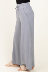 woman wearing light gray wide leg lounge pants with a drawstring waist and side pockets