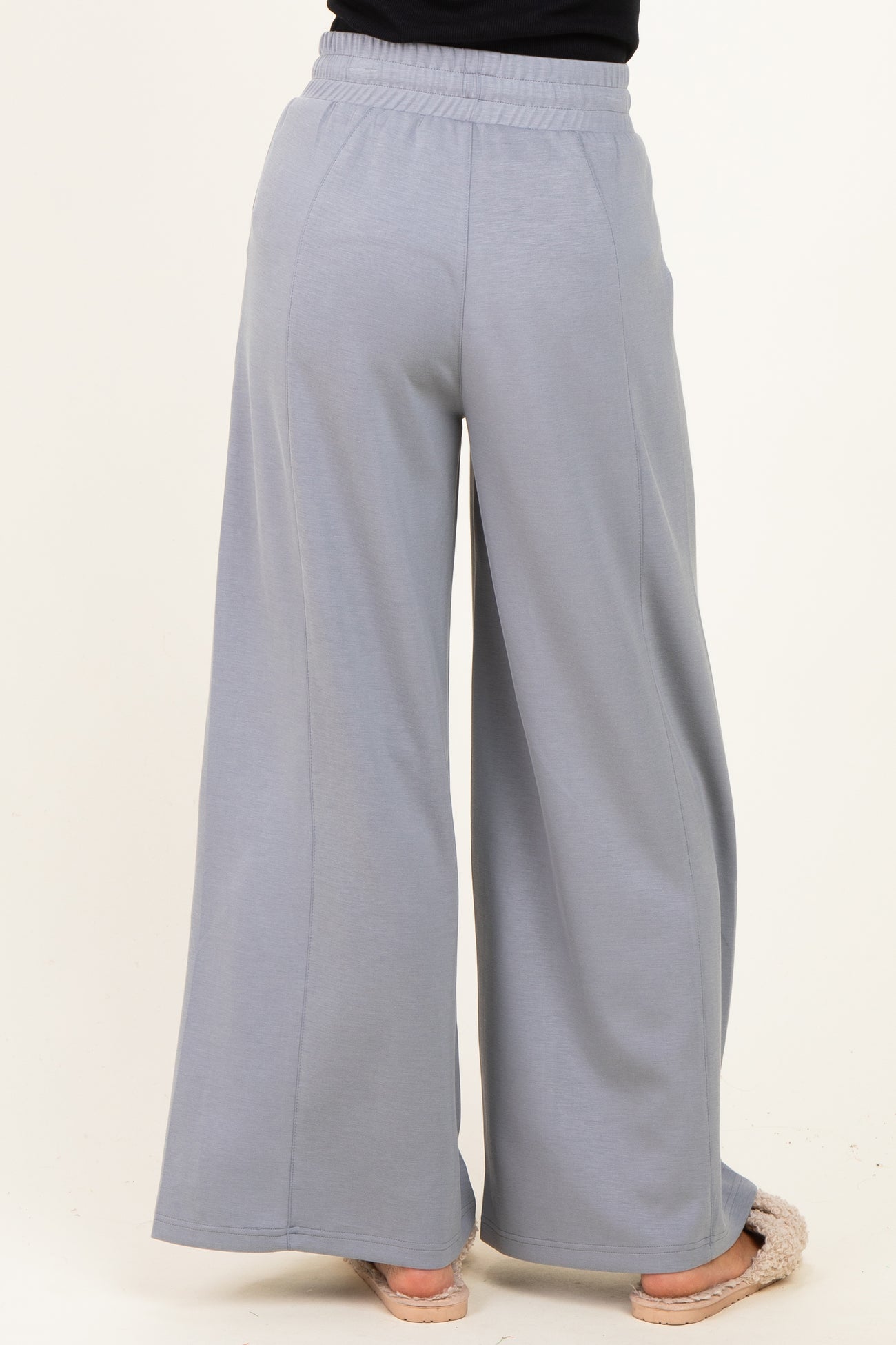 woman wearing light gray wide-leg sweatpants, seen from the back, with an elastic waistband and relaxed fit