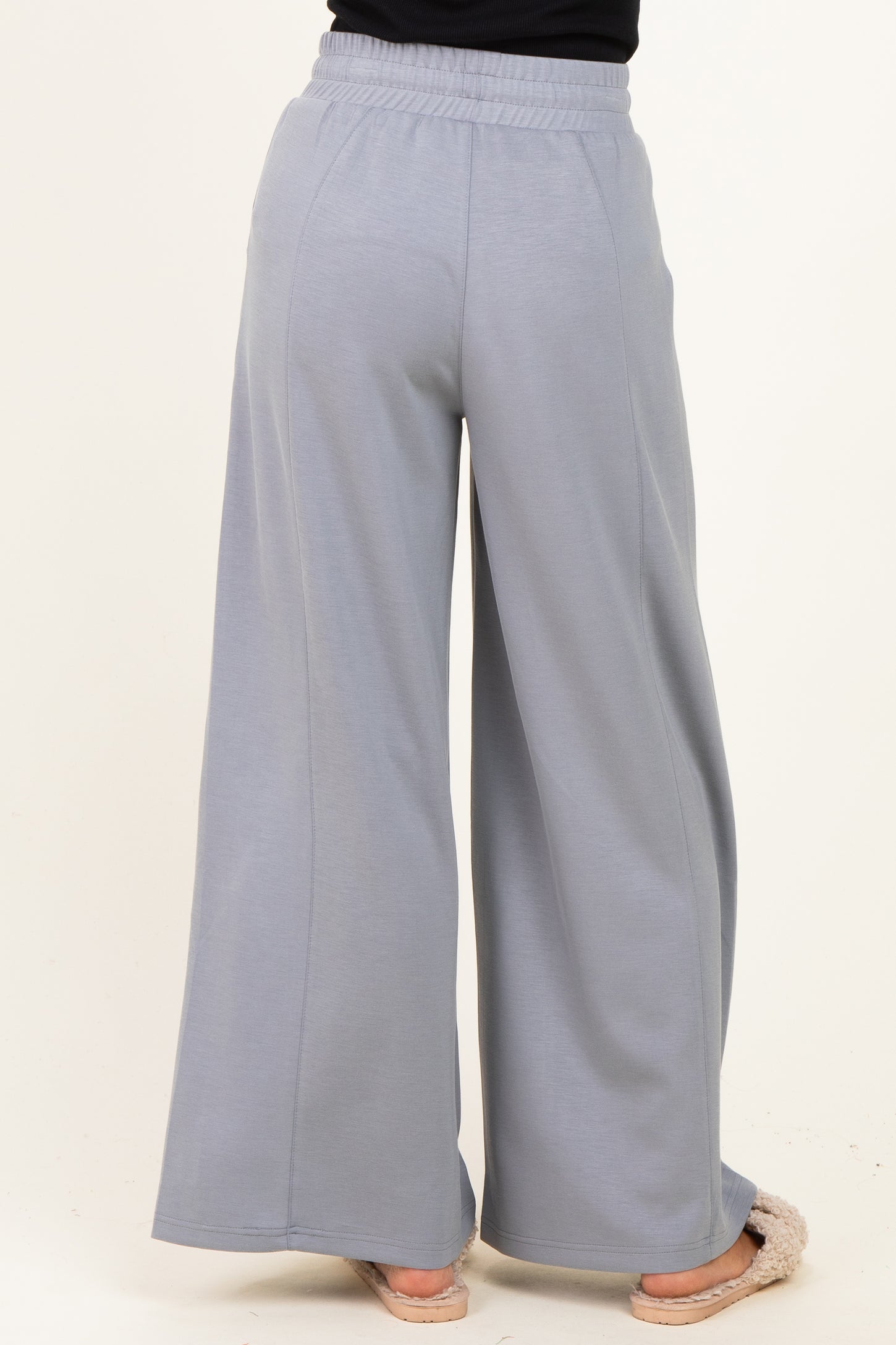 woman wearing light gray wide-leg sweatpants, seen from the back, with an elastic waistband and relaxed fit