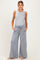woman wearing a light gray sleeveless maternity top and wide-leg maternity pants with pockets, showing her baby bump