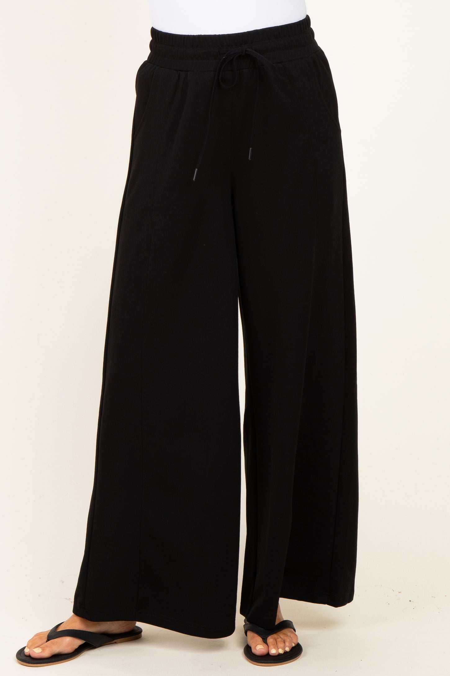woman wearing black wide-leg sweatpants with an adjustable drawstring waistband and flip-flops