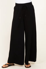 woman wearing black wide-leg sweatpants with an adjustable drawstring waistband and flip-flops