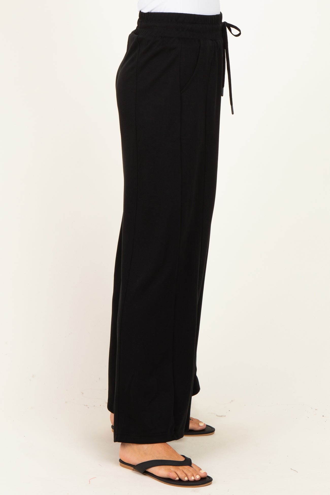 woman wearing black wide-leg lounge pants with an elastic waistband and drawstring detail