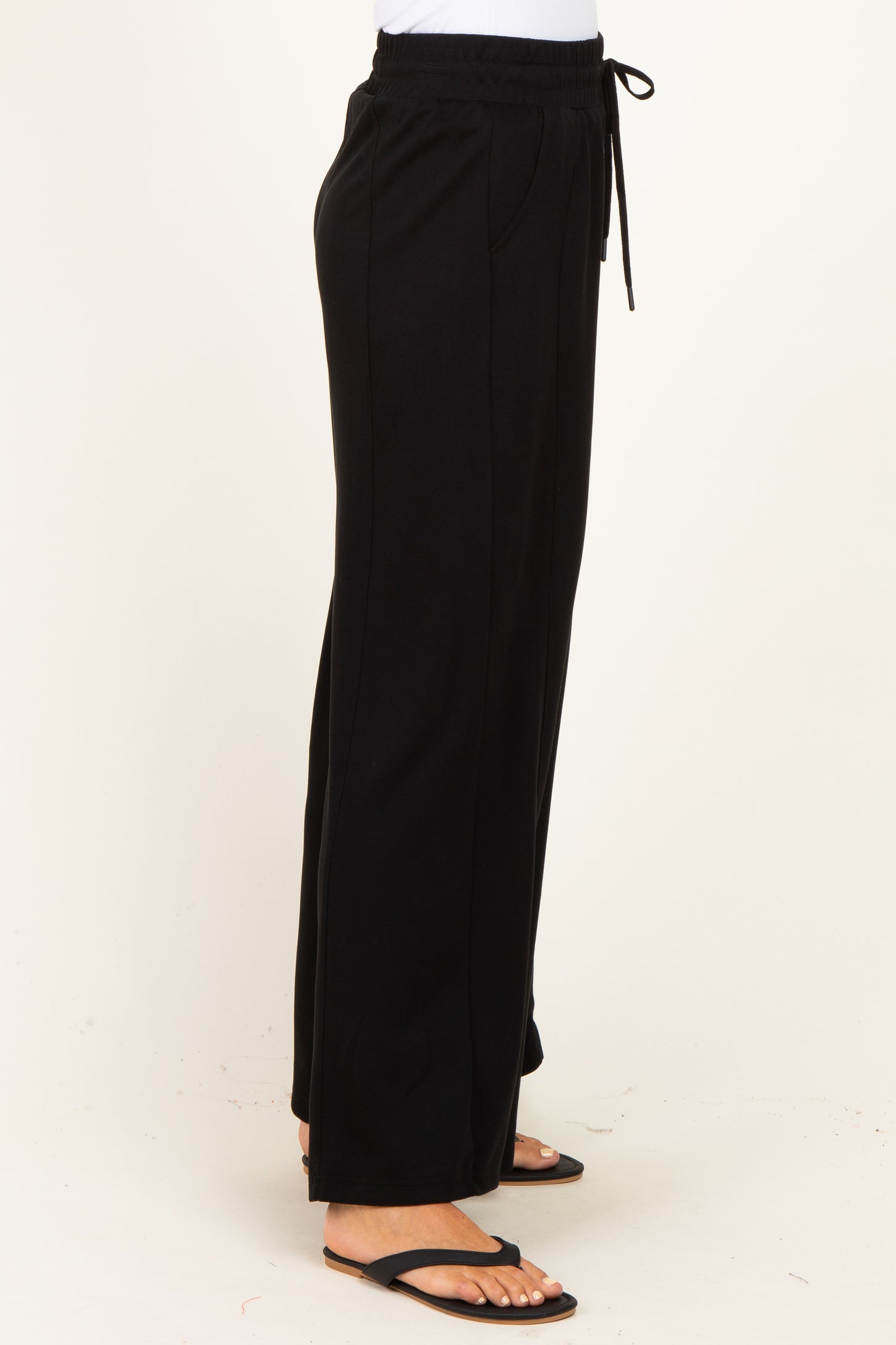woman wearing black wide-leg lounge pants with an elastic waistband and drawstring detail