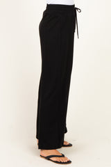 woman wearing black wide-leg lounge pants with an elastic waistband and drawstring detail