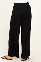 woman wearing black wide-leg pants, seen from the back, with an elastic waistband and relaxed fit