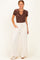 woman wearing a brown short sleeve henley top and white wide-leg pants with side pockets