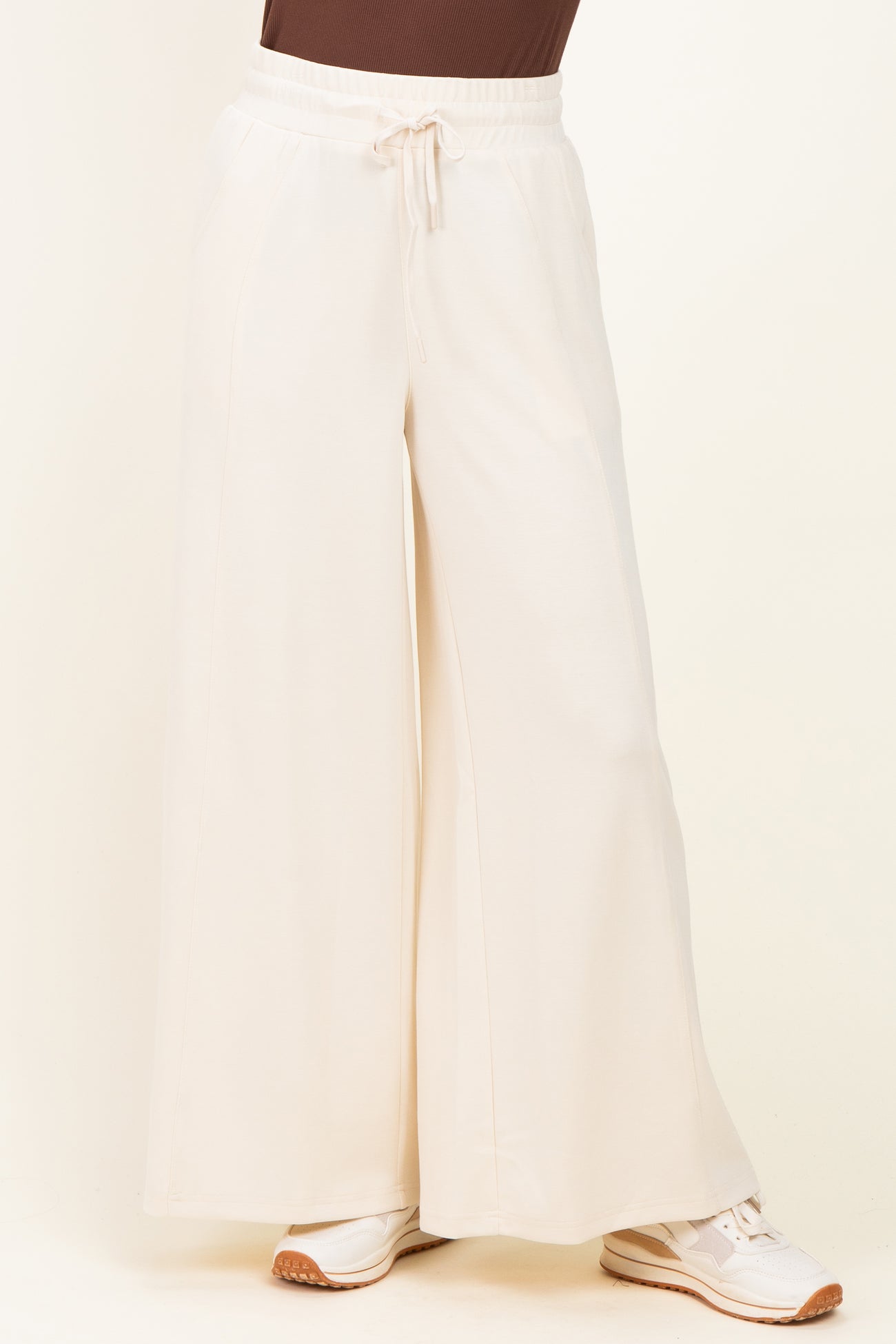 woman wearing cream wide-leg jogger pants with an elastic waistband and drawstring detail