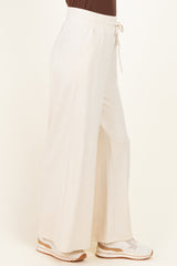 woman wearing white wide-leg lounge pants with side pockets and drawstring waist