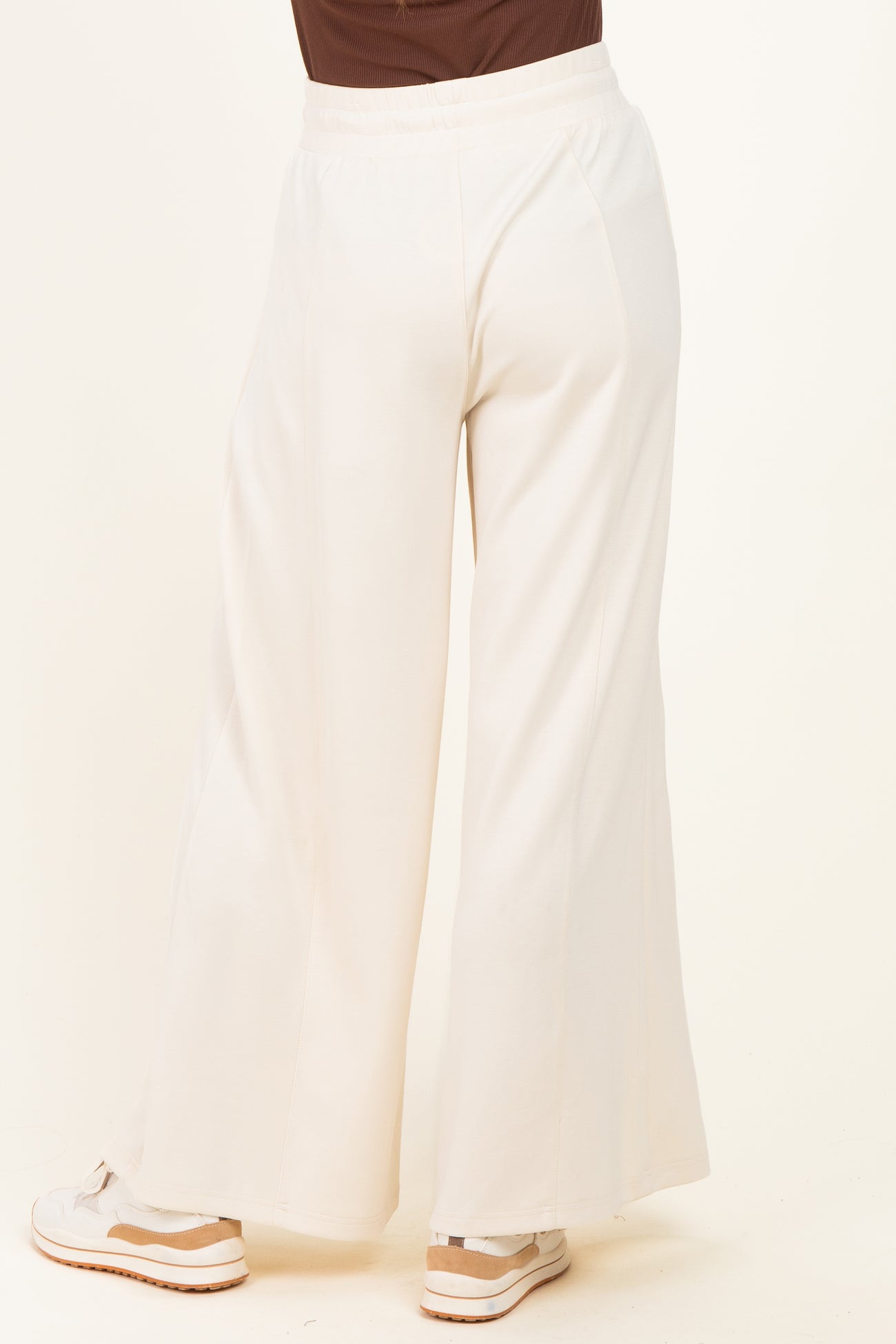 woman wearing white wide-leg pants viewed from the back, paired with sneakers
