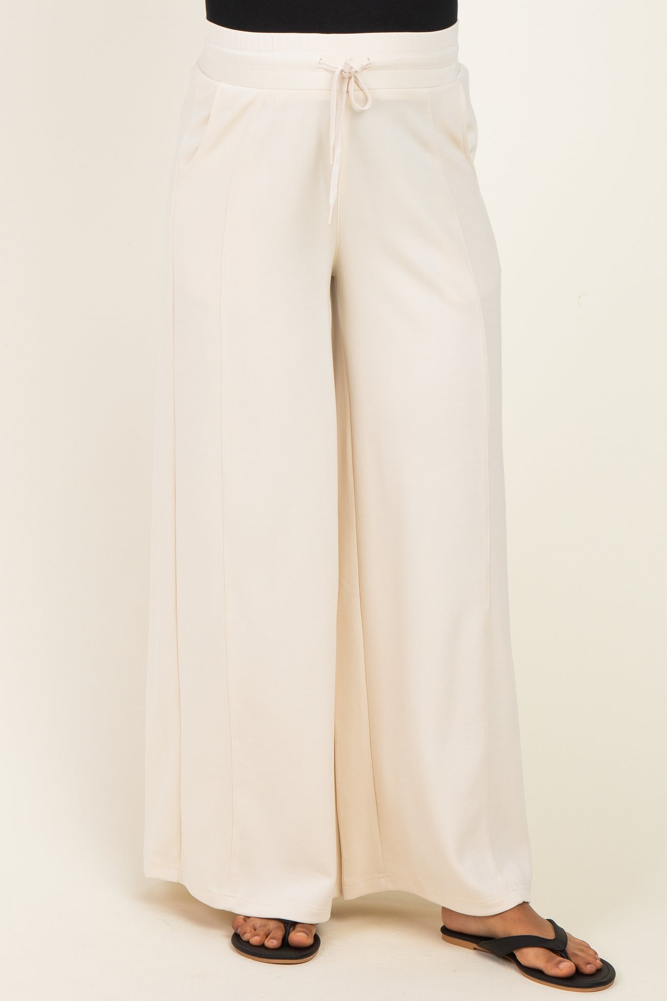 woman wearing cream wide-leg maternity pants with an elastic waistband and drawstring detail