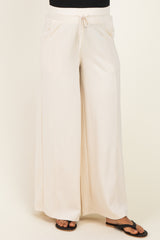 woman wearing cream wide-leg maternity pants with an elastic waistband and drawstring detail