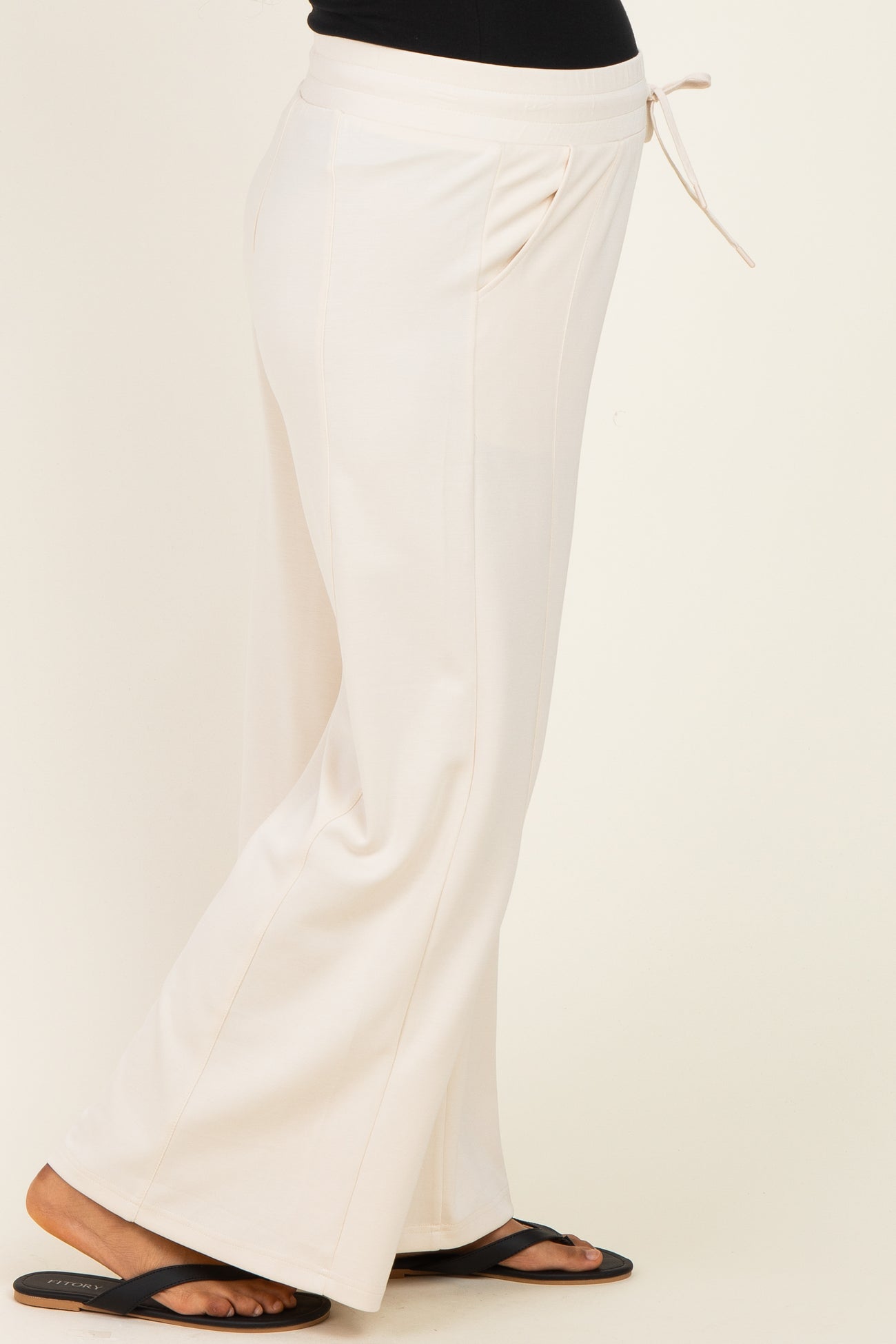 woman wearing cream maternity lounge pants with a drawstring waist and side pockets