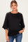 woman wearing a black maternity top with sheer sleeve details and a baby bump visible
