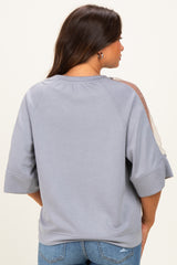 woman wearing a grey maternity sweatshirt with sheer panel details on the sleeves, seen from the back