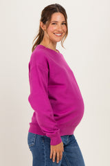woman wearing a hot pink maternity sweater and blue jeans with a visible baby bump